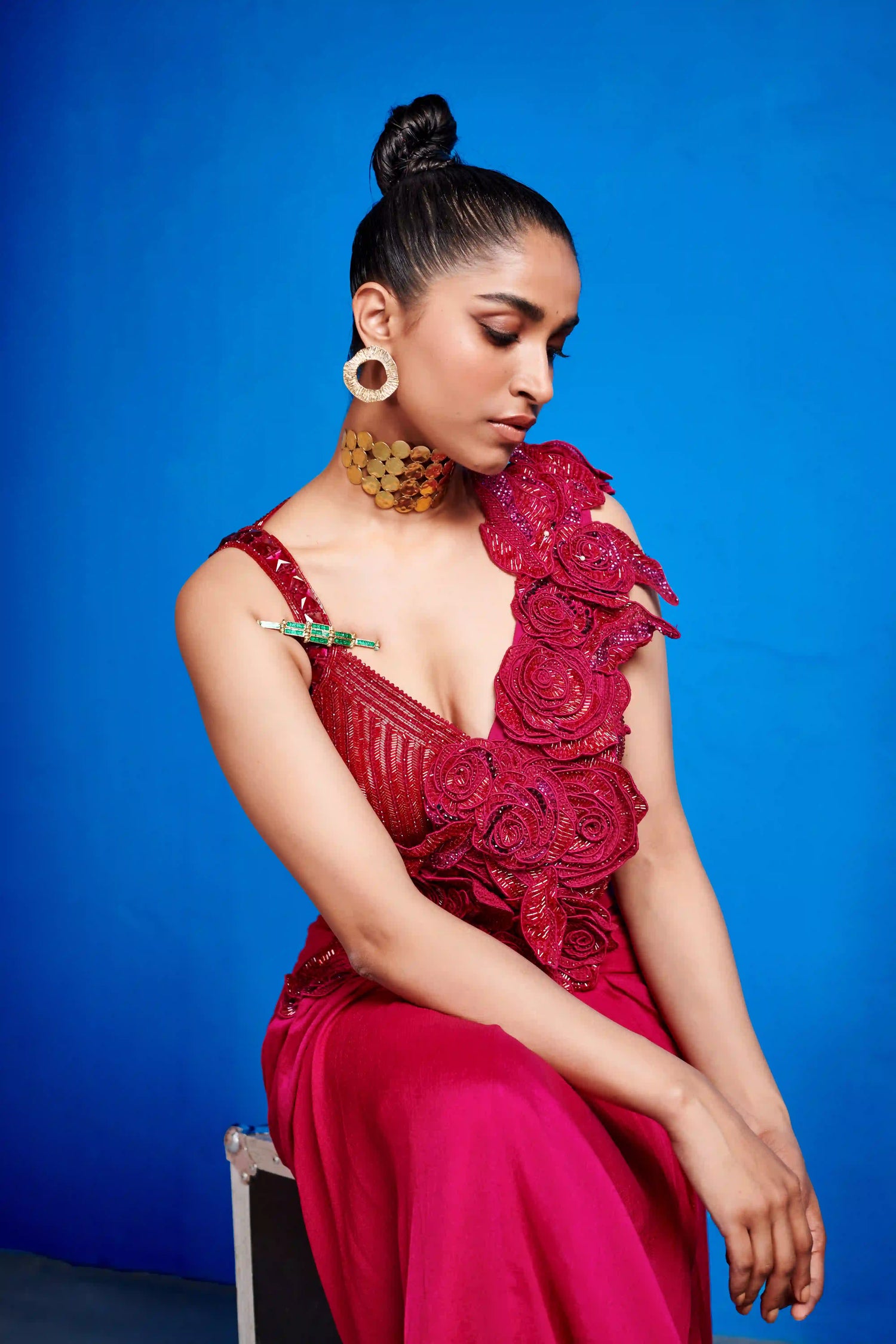 Woman in a red floral dress sitting against a blue background